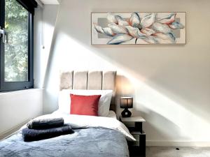 ein Schlafzimmer mit einem Bett mit einem roten Kissen in der Unterkunft Contemporary Designer 2 Bed Apartment, Free Parking, Gym, Yoga & Cinema Room in Bedford