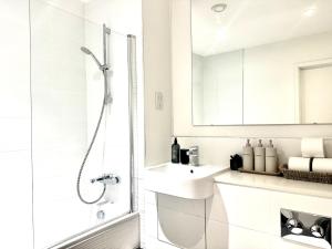 ein weißes Badezimmer mit Waschbecken und Dusche in der Unterkunft Contemporary Designer 2 Bed Apartment, Free Parking, Gym, Yoga & Cinema Room in Bedford + 27 Fotos
