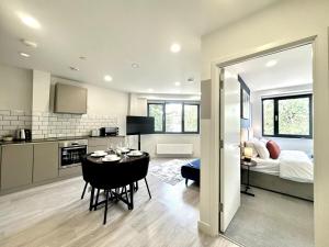 eine Küche und ein Wohnzimmer mit einem Tisch in einem Zimmer in der Unterkunft Contemporary Designer 2 Bed Apartment, Free Parking, Gym, Yoga & Cinema Room in Bedford