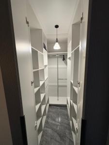 ein Bad mit einer ebenerdigen Dusche und einem begehbaren Kleiderschrank in der Unterkunft ЖК Панорама Парк Костанай in Qostanai