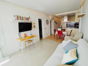a living room with a white couch and a table at Sunset Ocean Playa del Ingles in Playa del Ingles