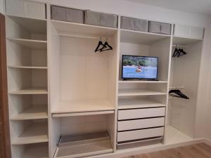 vestidor con estanterías blancas y TV en La casa de Teresa, en Santiago de Compostela
