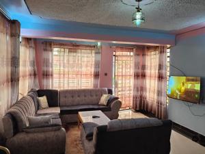 a living room with a couch and a tv at Balozi Homes Nyeri in Nyeri