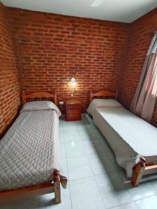 two beds in a room with a brick wall at 4 Estaciones in Pergamino
