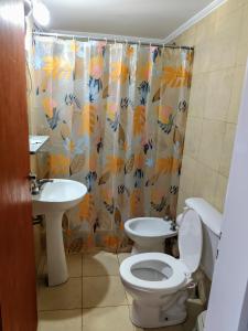 a bathroom with a toilet and a sink and a shower curtain at 4 Estaciones in Pergamino