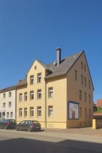 a large yellow building with cars parked in front of it at Casa Mateo Mediterranes Studio in Bielefeld