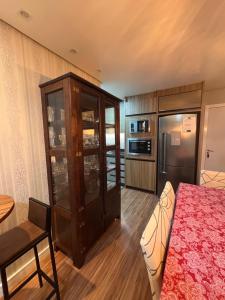 une chambre avec un lit, un réfrigérateur et une table dans l'établissement Apto no Coração de Criciúma, à Criciúma