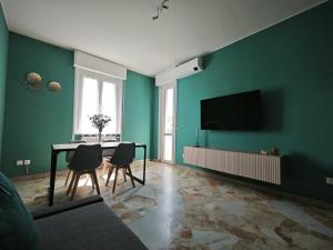 Una sala de estar con una mesa y un televisor en una pared verde. en Casa Augusta, en Milán
