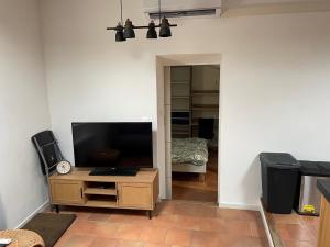 a living room with a flat screen tv on a wooden cabinet at Chambre calme, climatisé, appartement N2 in Avignon
