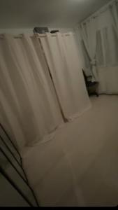 a white bed with white curtains in a room at Appartement de Myriam in Mons-en-Baroeul