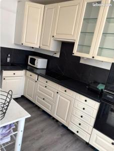 a white kitchen with white cabinets and a microwave at Appartement de Myriam in Mons-en-Baroeul