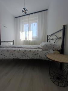 a bedroom with a bed and a table and a window at Apartman Maja 46 in Doboj +4 photos