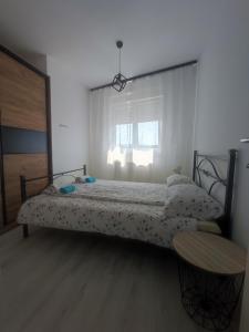a bedroom with a bed and a table and a window at Apartman Maja 46 in Doboj