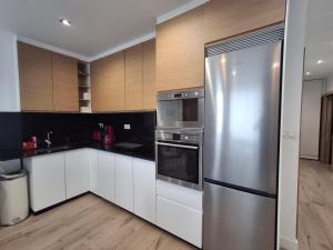 una cocina con nevera de acero inoxidable y armarios blancos en La casa de Teresa, en Santiago de Compostela