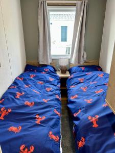 two beds in a room with blue sheets with crabs on them at Blosseys Beach House in South Hayling