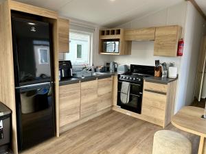 a kitchen with wooden cabinets and a black refrigerator at Blosseys Beach House in South Hayling +20 photos
