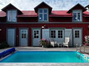 a red house with a swimming pool in front of a house at Tre Små Rum i Trosa in Trosa