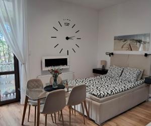 a bedroom with a bed and a table and a clock at Apartament MIODOWY przy plaży in Krynica Morska
