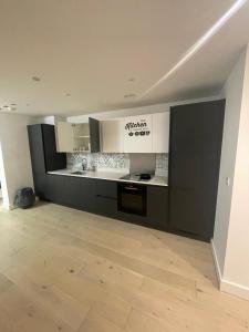 una cucina con armadietti bianchi e neri e pavimenti in legno di Spacious Flat for Professional a Slough