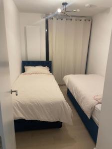 2 letti in una piccola camera con pareti bianche di Spacious Flat for Professional a Slough
