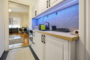 a kitchen with white cabinets and a blue wall at Piac 16 apartman a belváros szívében in Debrecen