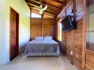 a bedroom with a bed and a flat screen tv at Chalé na Cachoeira dos Machados II - Bueno Brandão in Bueno Brandão