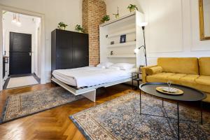 a bedroom with a bed and a couch and a table at Piac 16 apartman a belváros szívében in Debrecen