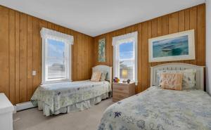 two beds in a bedroom with wooden walls and windows at 3 Bedroom 2 bath Beach House condo- 10 houses from the beach walk to the beach in Seaside Park