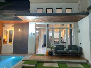 a villa with a swimming pool and two chairs at eHouse in Banyuwangi