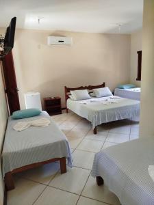 a hotel room with two beds and a tv at Pousada da Paz in Itacaré