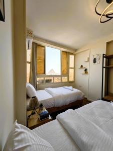 开罗GEM Pyramids & Grand Museum View的有两张床和一扇窗户的酒店房间 更多73张照片