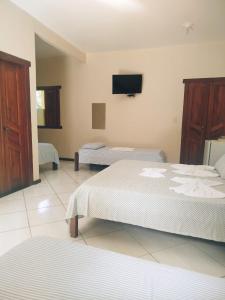 a bedroom with two beds and a flat screen tv at Pousada da Paz in Itacaré