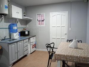 a kitchen with white cabinets and a table and a table and a door at Deptos Los Alerces in General Villegas