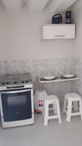 a kitchen with a stove and two stools at Loft Lagoa Areal in Araruama