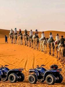a group of people riding camels in the desert at Merzouga Nature Camp in Merzouga
