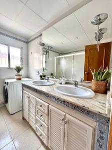 a bathroom with two sinks and a washer and dryer at Serena Villa in Benicarló