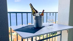 a table with two bottles and glasses on a balcony at Mãe de Deus - Caniço - Madeira in Caniço