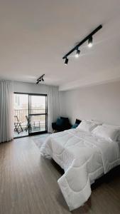 a white bedroom with a large bed and a balcony at ZYZ - Centro in Sao Paulo