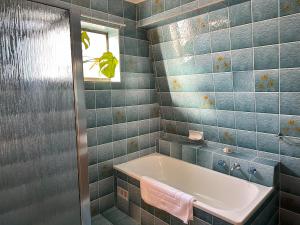 a blue tiled bathroom with a tub and a window at Suur Kodu- Beachfront House plus Tiny Home in Sellicks Beach +38 photos