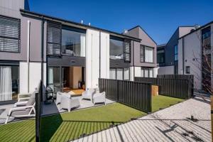 a house with white chairs and a yard at Wanaka Getaway - Bright 2-Bed Apartment in Wanaka