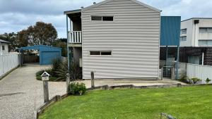 a white house with a yard next to a building at Dolphin in Apollo Bay