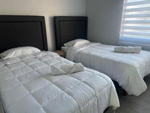 two beds with white sheets in a bedroom at Casa equipada Vallenar in Vallenar