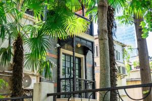 a house with palm trees in front of it at A detached, old Shanghai villa on Huaihai Middle Road in Shanghai