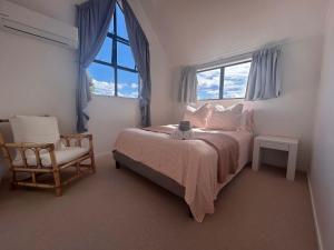 a bedroom with a bed with a chair and a window at A Hidden Gem in Auckland