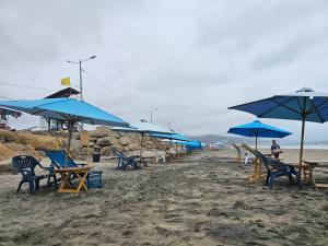 a group of blue umbrellas and chairs on a beach at Casa Moderna en Crucita la Bella in Crucita