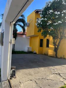 ein gelbes Gebäude mit einem Baum davor in der Unterkunft Beira Mar in Aracaju