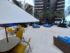 a patio with chairs and tables and an umbrella at Landscape Beira Mar in Fortaleza