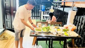 a man preparing food on a table on a patio at AHK Homestay 5 in Phu Quoc