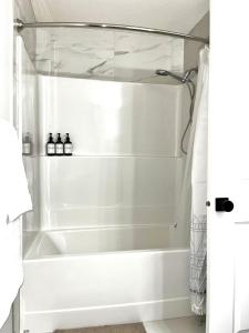 a white bath tub in a bathroom with a shower at Affordable Cozy Bedroom Close to YYC Airport in Calgary