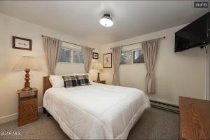 a bedroom with a white bed and a flat screen tv at Quaint townhome in downtown Winter Park, Ski and Bikers Paradise, Walk to Town in Winter Park